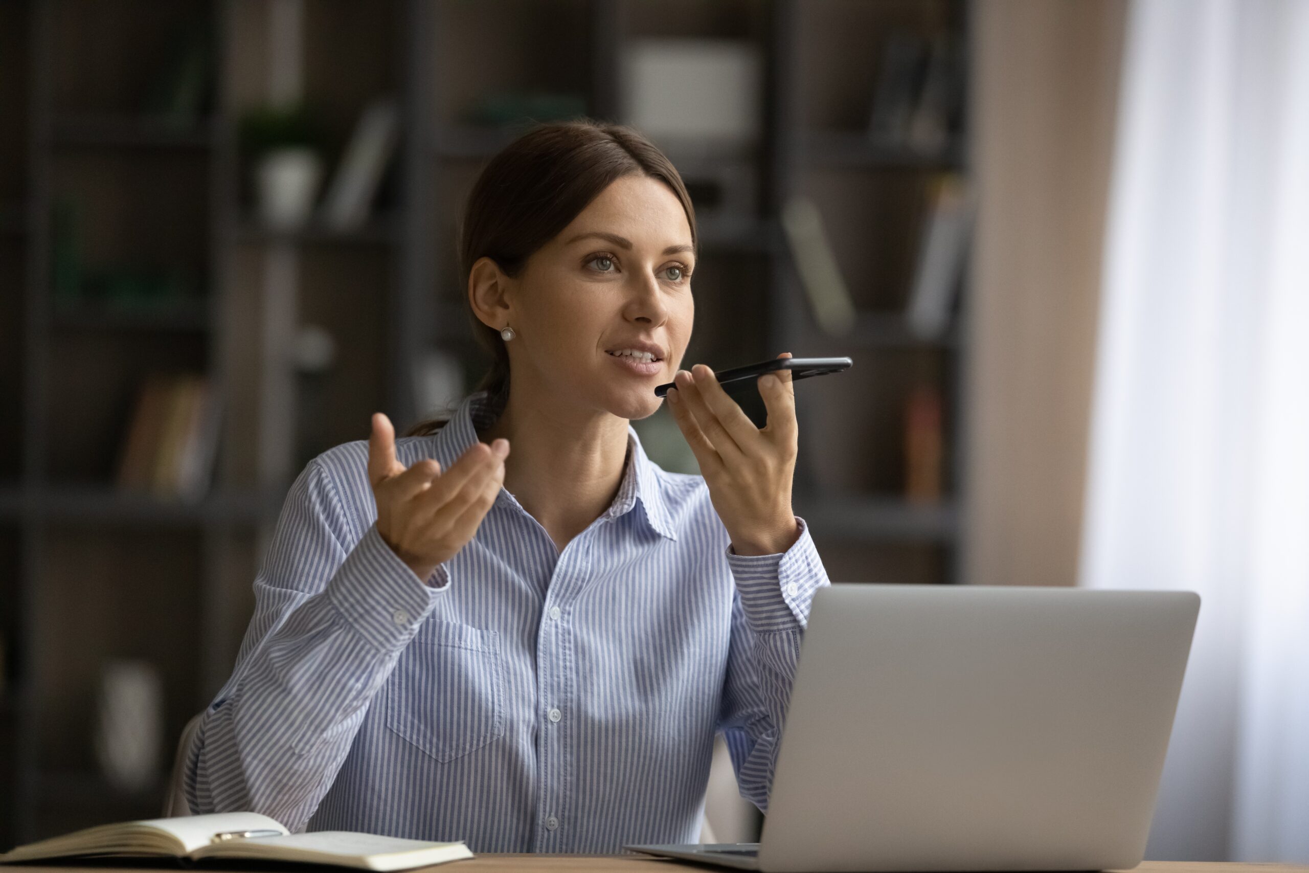Attractive,Young,Woman,Sit,At,Desk,Holding,Smart,Phone,Talk